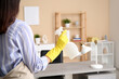 © Pixel-Shot - Woman with spray bottle of detergent in living room