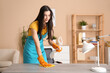 © Pixel-Shot - Young woman cleaning desk with rag in living room