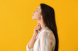 Young woman with thyroid gland problem on yellow background
