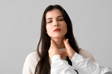 Wall Mural - Endocrinologist examining thyroid gland of young woman on grey background