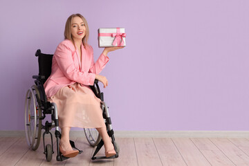 Sticker - Young woman in wheelchair with gift box near lilac wall. International Women's Day