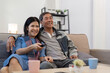 © Natee Meepian - Asian senior couple enjoying in their favorite TV. Happy retirement couple watching television together in living room