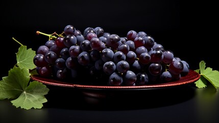 Sticker - Black grapes on a plate on a black background. Studio shot.