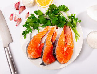 Wall Mural - Fresh uncooked salmon fish with greens and lemon on a ceramic plate with kitchen knife