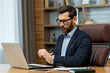 © Liubomir - Tired entrepreneur in formal clothes massaging wrist with hand after long day of using laptop. Successful copywriter having spasms in palm muscles after typing on pc and answering emails in workplace.