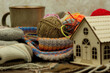 Yarn, a knitted scarf, and a toy house symbolize a cozy environment. Knitting is a type of needlework. Yarn for knitting in the cold season.