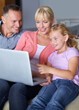 © Mapodile M./peopleimages.com - Happy family, laptop and sofa in living room on internet and streaming subscription in apartment. Daughter, woman or man with pc by online video on couch, bonding or technology with love in house