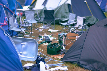 Tents, trash and mess at an outdoor music festival or event for a celebration party or social gathering. Summer, campsite and dirty with untidy camping gear, chairs or cooler boxes on the ground