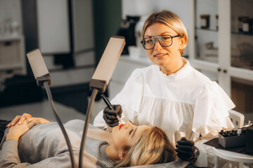 Wall Mural - Smiling woman makes permanent makeup to another woman