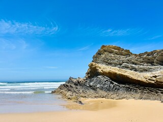 Rocky ocean coast, ocean bay with rocky coast and sand beach, blue sky, no people