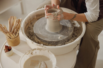 Close up of hands of professional potter molding pot shape on pottery wheel. Ceramics art concept