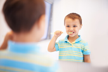 Wall Mural - Boy child, brushing teeth and mirror in bathroom for cleaning, hygiene or health for routine in home. Kid, toothbrush or reflection for dental wellness, smile or results in morning at family house