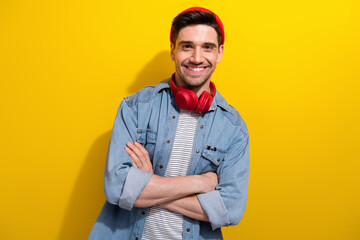 Wall Mural - Photo of funky confident man dressed jeans shirt arms folded listening song earphones isolated yellow color background