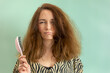 Woman struggling with fizzy hair combing, holding hair brush.