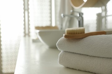 Poster - Stack of clean towels and massage brush on countertop in bathroom. Space for text