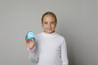 © millaf - Happy young child girl holding invisalign transparent retainers with a blue box on white studio wall  background
