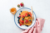 Fototapeta Desenie - Breakfast pancakes with fresh berries and honey on light grey background, top view