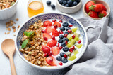 Fototapeta Desenie - Granola bowl with berries, pomegranate and kiwi. Healthy superfood breakfast bowl