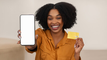 Wall Mural - Smiling millennial african american curly woman show credit card and smartphone