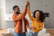 © Prostock-studio - Cheerful millennial black spouses having fun together dancing in kitchen