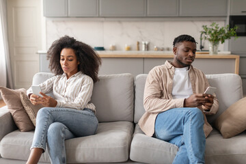 Wall Mural - Displeased Bored African American Couple Using Smartphones Sitting At Home