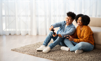 Wall Mural - Cheerful young african american woman and man gamers play at computer game with joystick