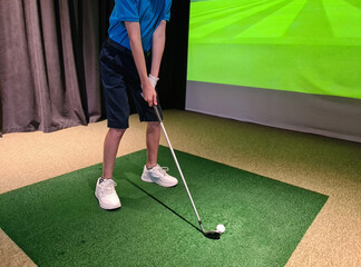 Wall Mural - Teen guy golfer plays golf on a golf simulator