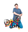 A man in casual clothes repairs a children's bicycle, holding a monkey wrench, isolated on a transparent background png
