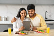 © Prostock-studio - Loving Indian Couple Eating Breakfast Together And Using Digital Tablet