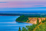 Fototapeta  - Seascape - the shore of Lake Onega in selective focus against the background of clouds at sunset.Karelian landscape.Concept of traveling around the Russian North.Nature, ecotourism.Forest lake.