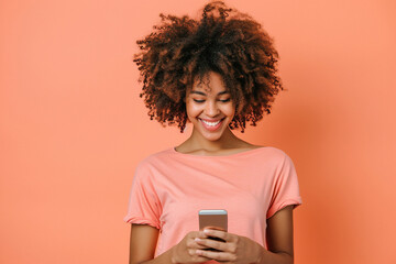 Casual African American woman on peach background using smartphone