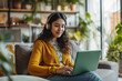 © wolfhound911 - Indian girl in headphones working on laptop with a smile at home