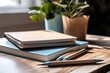 © Lasvu - Blue and brown notepads with vacant spaces up close on the desk. Mockup of a white table with a stack of notebooks and green brush leaves