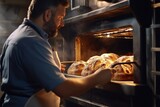 Fototapeta  - A man is pictured taking a loaf of bread out of an oven. This image can be used to showcase the process of baking bread or for illustrating homemade baking