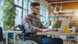 Portrait of disabled male office worker in a wheelchair looking at the screen of his laptop while performing in co-working space