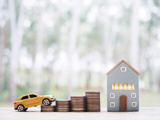 Poster - Miniature house and wooden toy car on stack of coins. The concept of saving money  for car and house