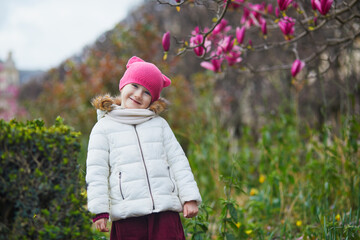 Wall Mural - Preschooler girl looking at pink magnolia in full bloom on a street of Paris, France