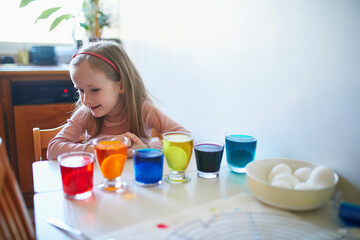 Wall Mural - Adorable preschooler girl dyeing Easter eggs at home