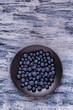 from above, on a textured background, a black plate with fresh blueberries. Empty space.