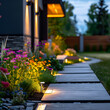 Modern gardening landscaping design details. Illuminated pathway in front of residential house. Landscape garden with ambient lighting system installation highlighting flowers plants.