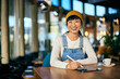 © bnenin - Portrait of a smiling Asian woman, using a digital tablet and a pen, making some designs online, working from the restaurant.
