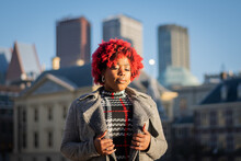 Sexy Moody Female Model With Strong Unique Style Appearance In Urban Inner City Environment The Hague Cityscape Skyline. Confident Black Lady Stylish Red Hair With Winter Good Taste Holland Fashion	