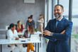 © Dragana Gordic - Portrait of smiling mid adult businessman standing at corporate office. Portrait of mature businessman at modern office. Happy mature business professional standing in modern office.