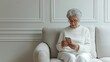 An old woman in white holds a phone in her hands, masters modern technologies uses. Advertising mobile dating apps for older single people