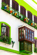 White and green house in Nerja, Andalusia. Colorful flowers on balconies.