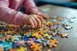 © MNStudio - Little girl playing puzzles at home. Child connecting jigsaw puzzle pieces in a living room table. Kid assembling a jigsaw puzzle. Fun family leisure.