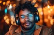 Close-up portrait of a young African-American man with dreadlocks wearing headphones and glasses, smiling at the camera.