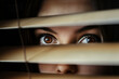 Terrified woman looking through window blinds outside. Privacy and intrusion concepts.