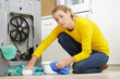 young woman holding napkin under sink pipe leakage