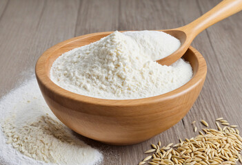 Flour-covered spoon in wooden bowl with rice or wheat flour on clear or white backdrop